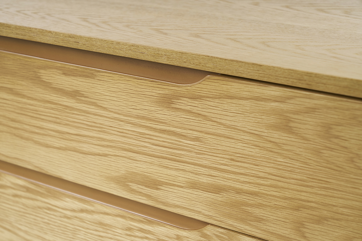 Primo piano della cassettiera scandinava in legno chiaro con maniglie integrate.