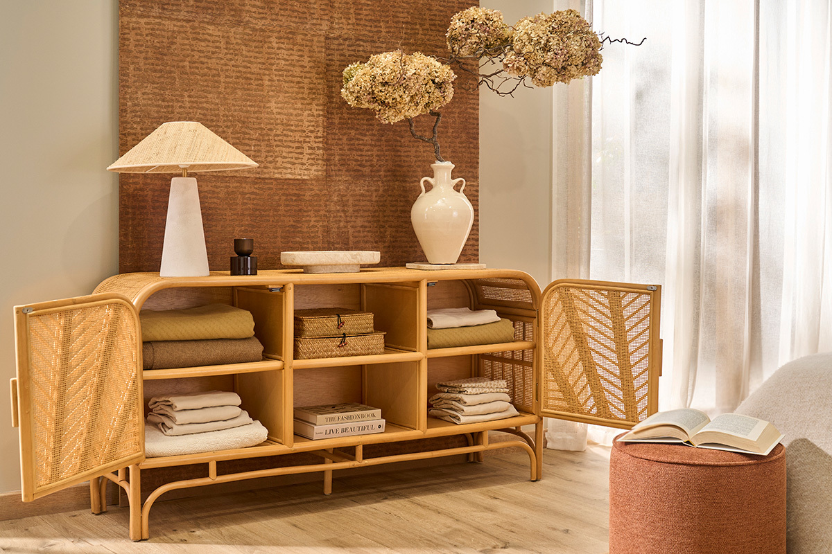 Buffet in rattan con porte aperte, oggetti decorativi sopra, in un interno luminoso.