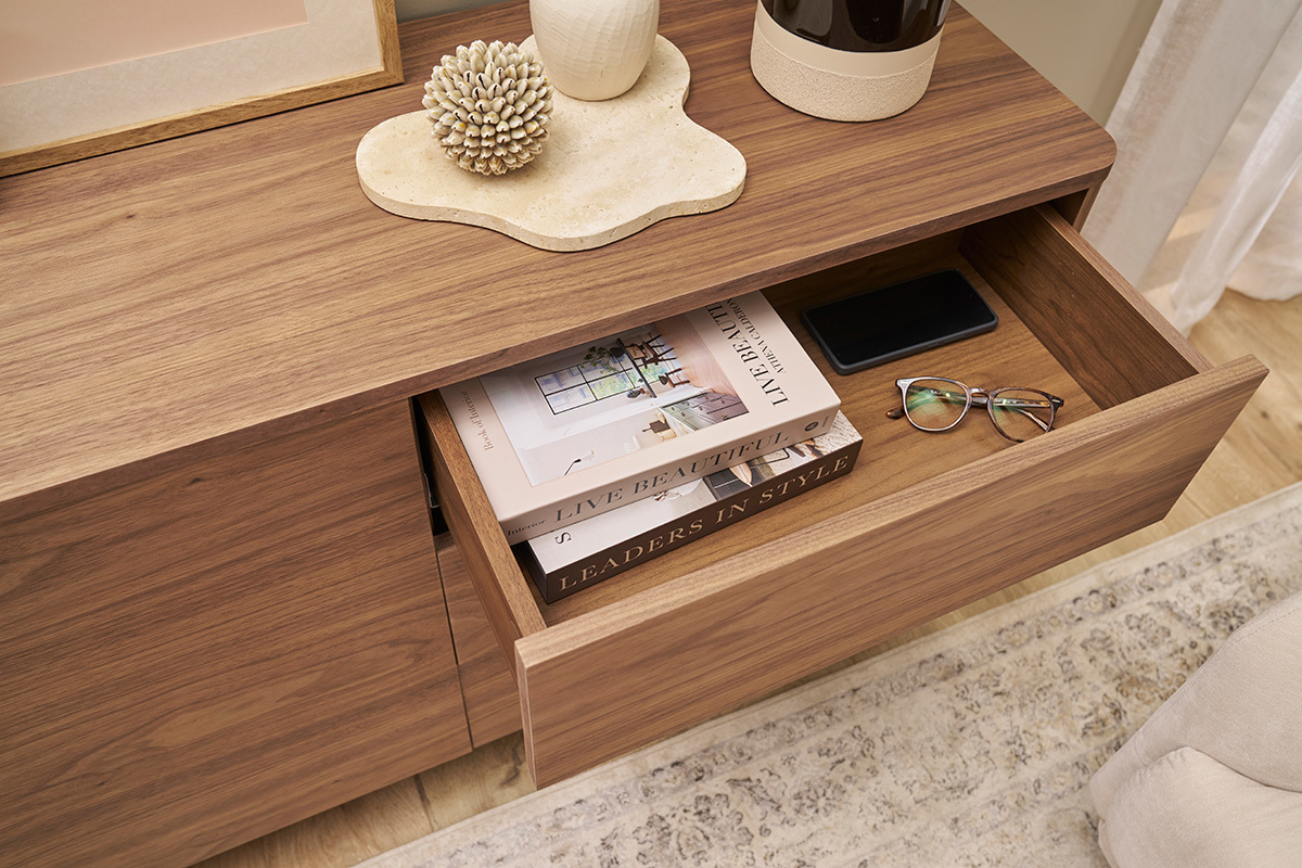 Buffet in legno scuro con cassetto aperto, libri e occhiali sistemati all'interno.
