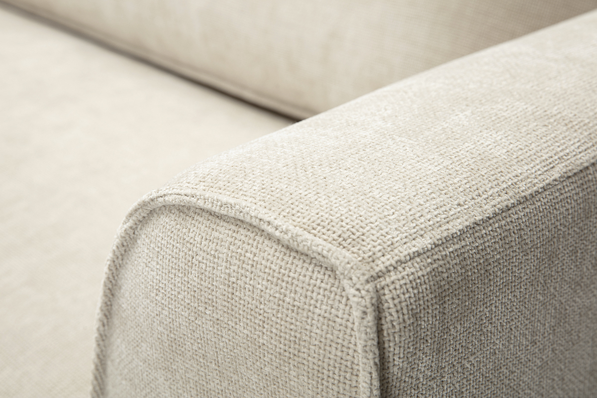Primo piano sul bracciolo di un divano in tessuto effetto velluto testurato beige.