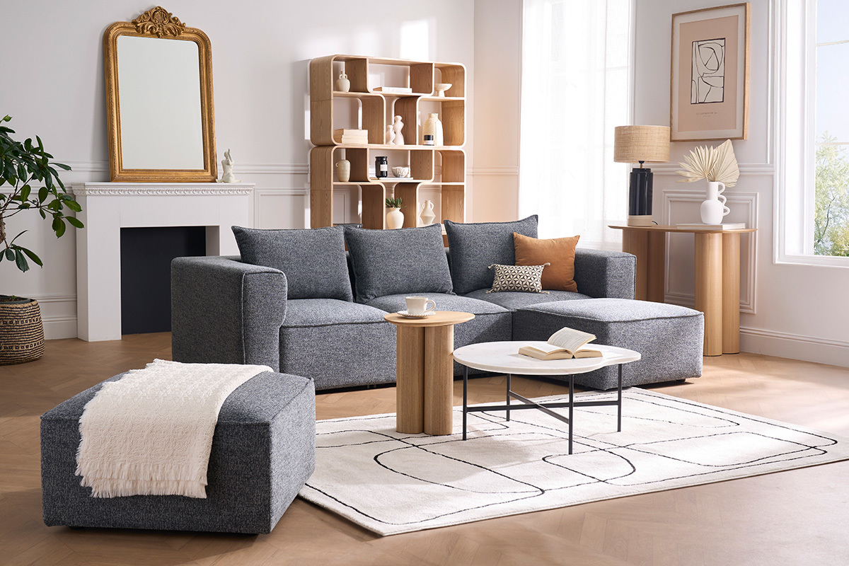 Divano angolare modulabile a 4 posti in tessuto grigio, presentato in un soggiorno moderno.