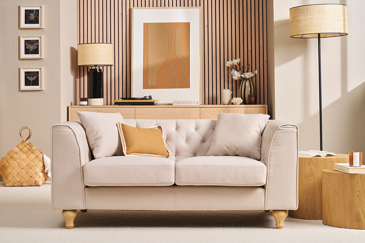 Divano a 2 posti trapuntato beige con cuscini, vista frontale.