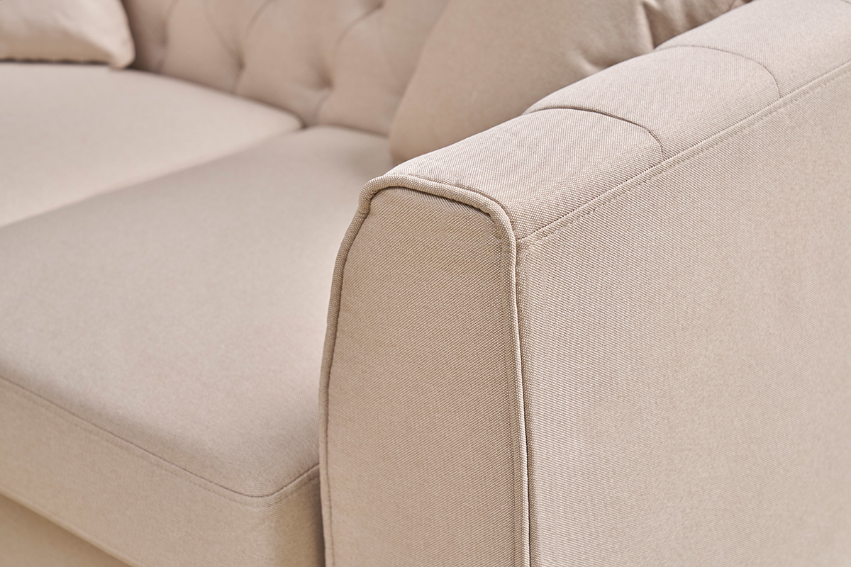 Primo piano sul bracciolo del divano a 2 posti MONTAIGNE in tessuto beige con capitonn.