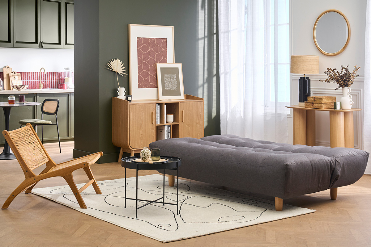 Divano letto grigio scuro a 3 posti, gambe in legno chiaro, situato in un salotto moderno.
