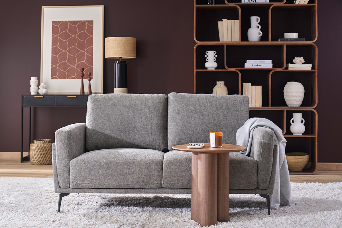 Divano di design a 2 posti grigio scuro con tavolino laterale in legno, decor moderno sullo sfondo.