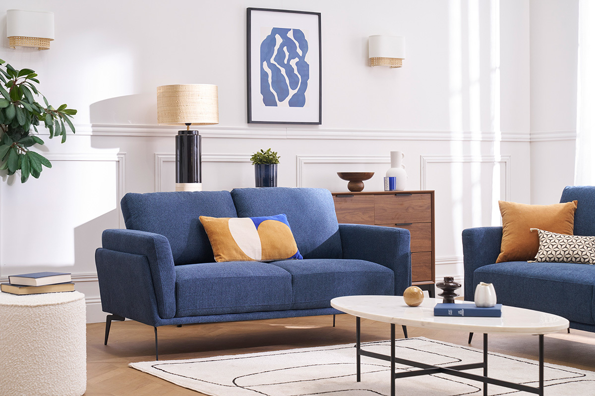 Divano design a 2 posti in tessuto blu in un soggiorno luminoso con tavolino e decorazione moderna.