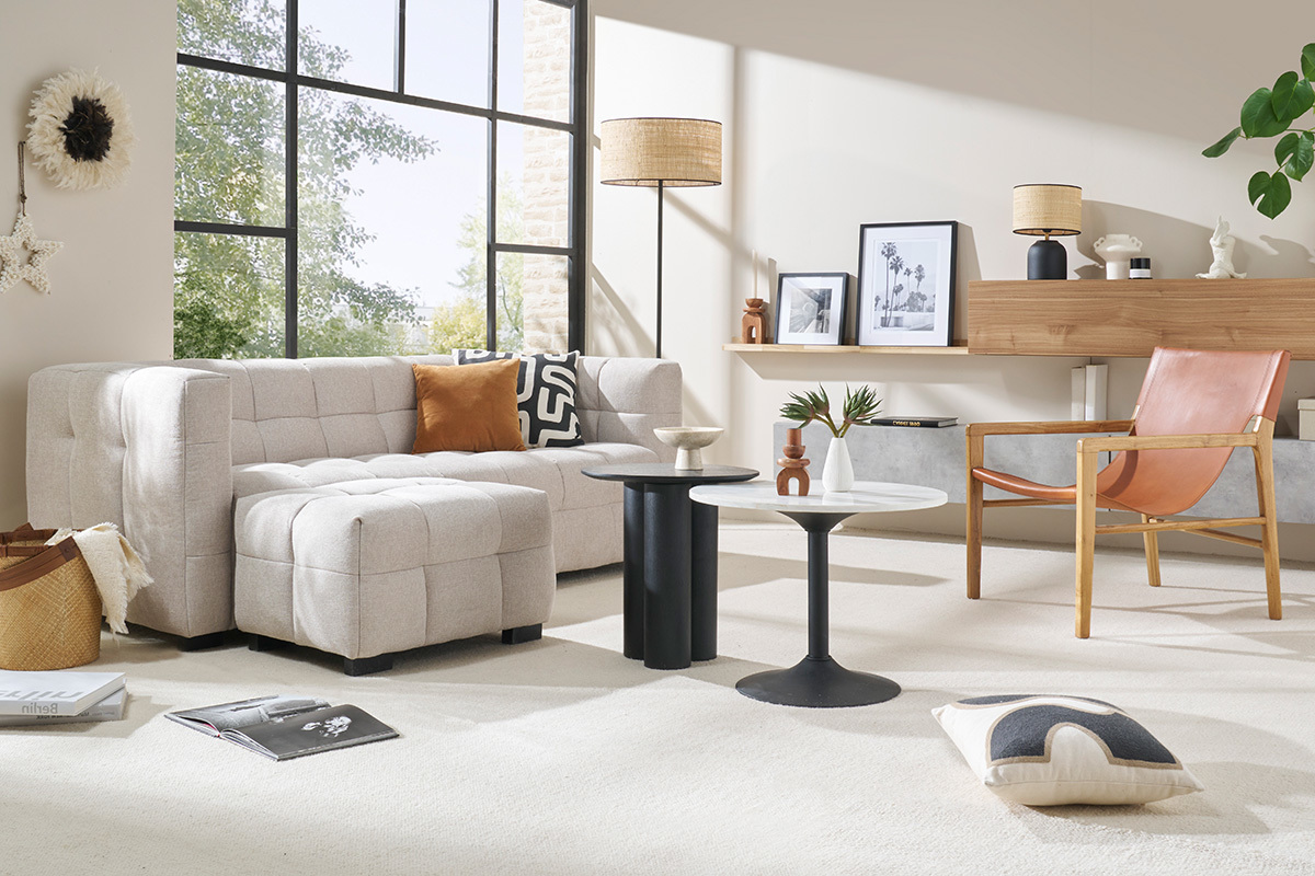 Soggiorno con divano in tessuto beige, lampada da terra, tavolino e poltrona in pelle.