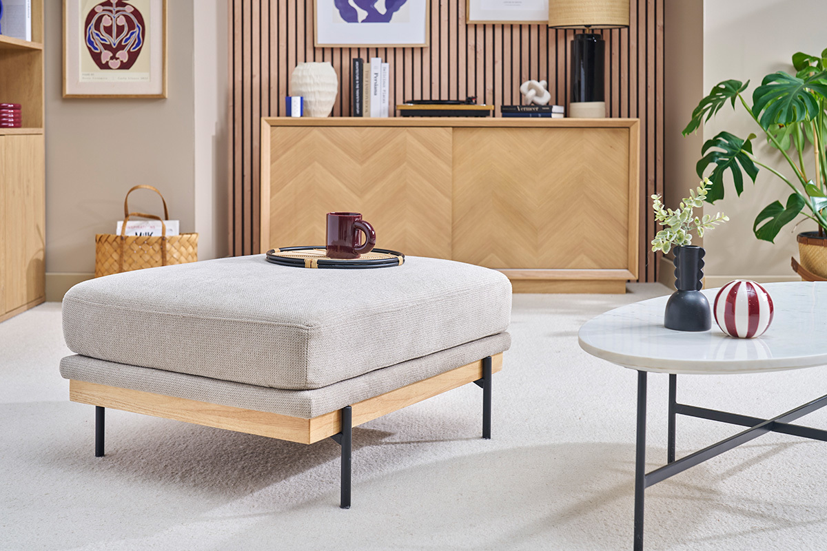 Poggiapiedi in tessuto ciniglia beige e metallo nero in un salotto elegante.