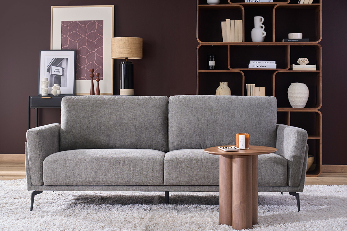 Divano di design a 3 posti in tessuto velluto grigio, vista frontale con tavolino decorativo