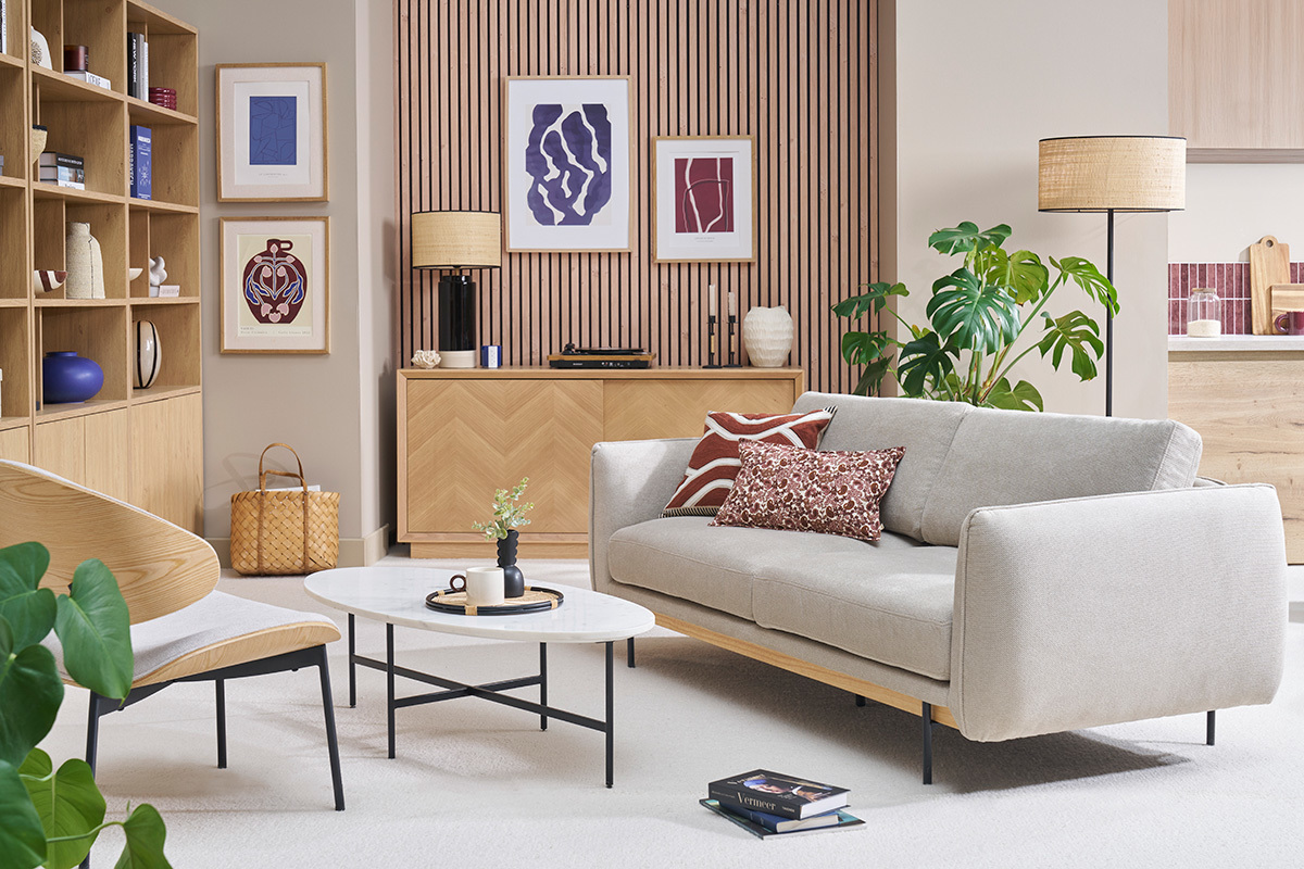 Divano design a 3 posti in tessuto beige con cuscini, vista frontale in un soggiorno moderno.