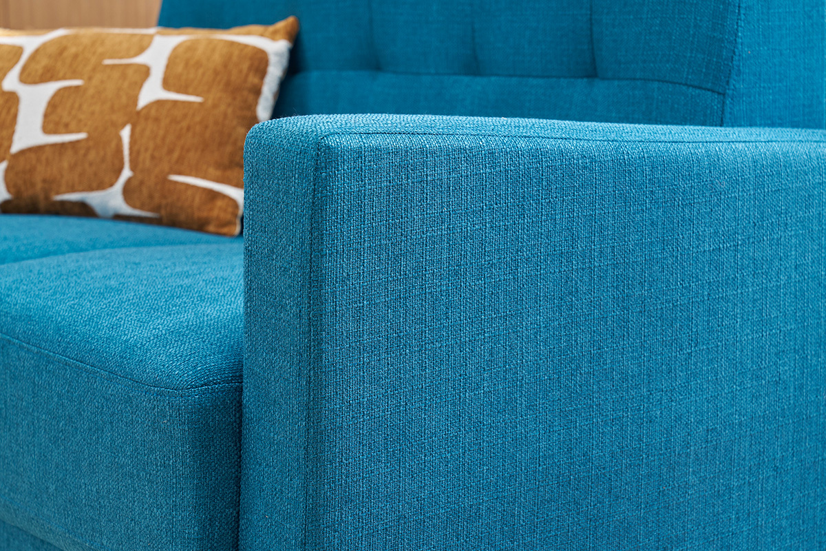 Divano scandinavo blu pavone con cuscino, vista laterale ravvicinata.