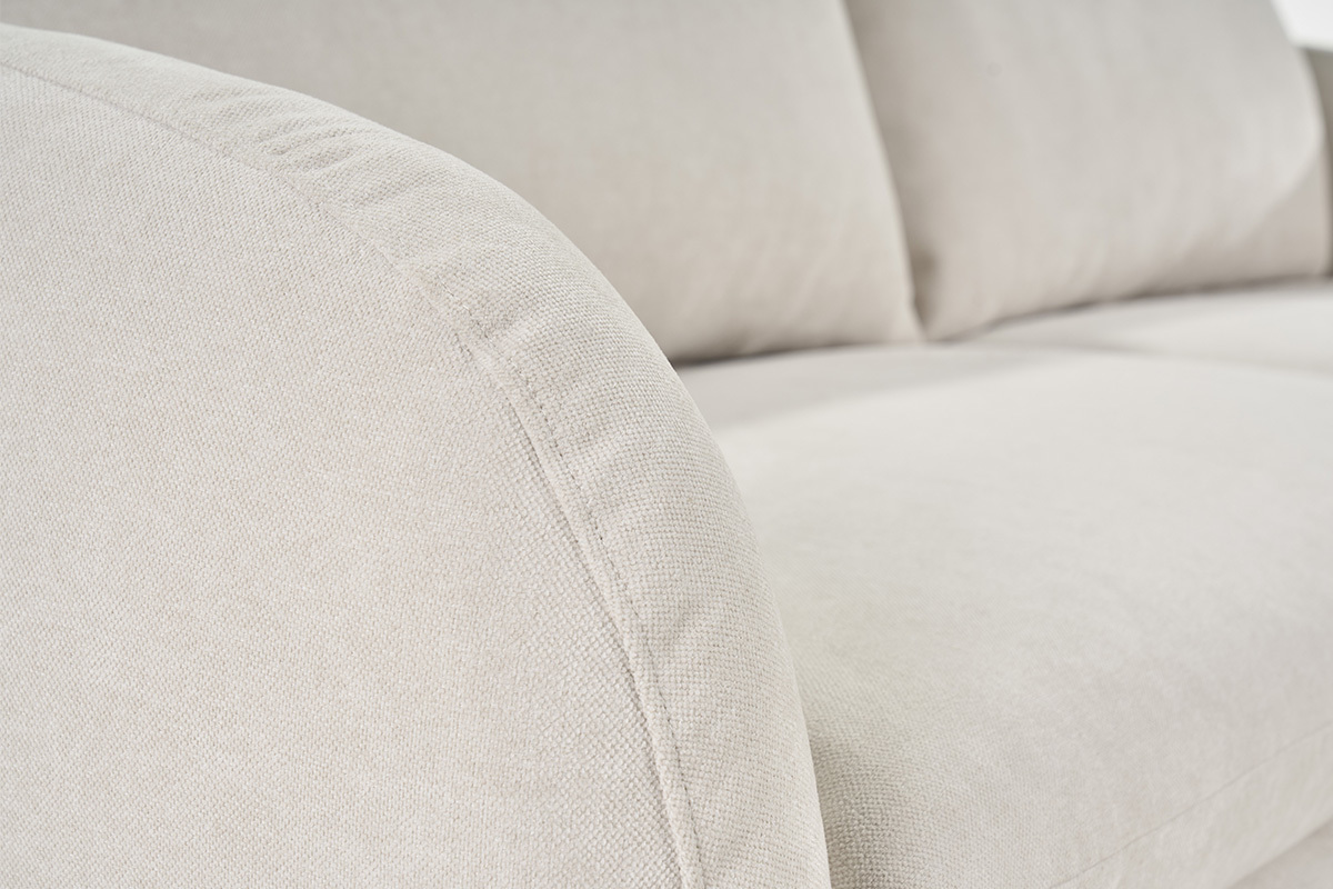 Primo piano sul divano in tessuto effetto velluto beige, bracciolo arrotondato.