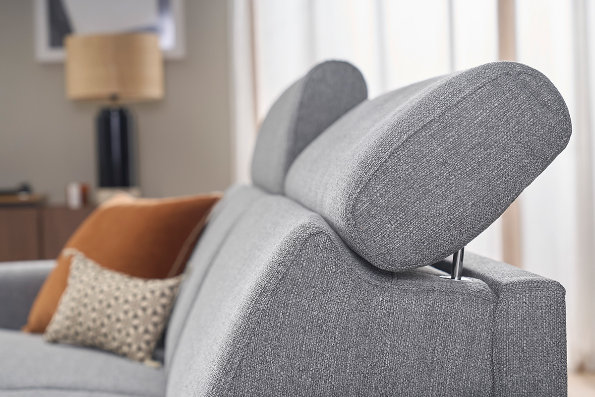 Dettaglio dei poggiatesta regolabili di un divano letto grigio chiaro, con cuscini decorativi.