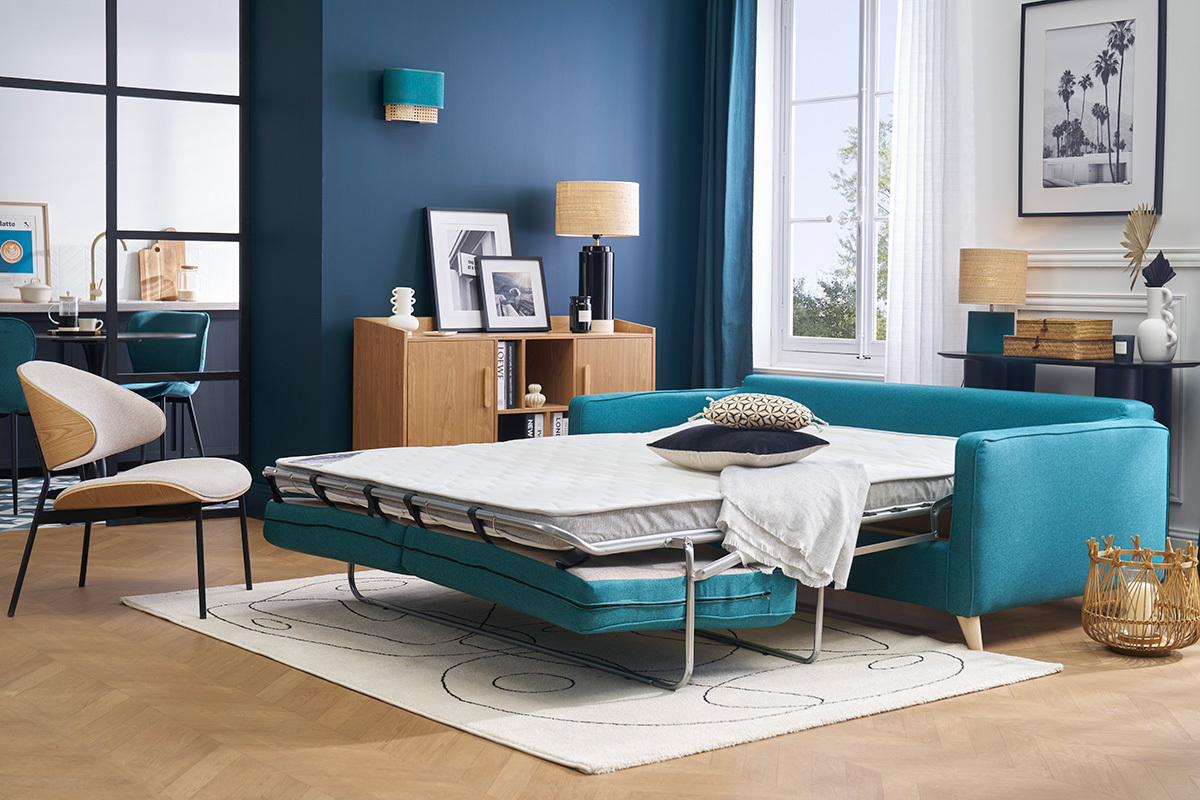 Divano letto scandinavo blu petrolio, materasso aperto, vista d'interno moderno.