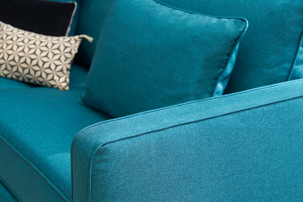 Divano scandinavo blu petrolio con cuscini geometrici, vista ravvicinata.