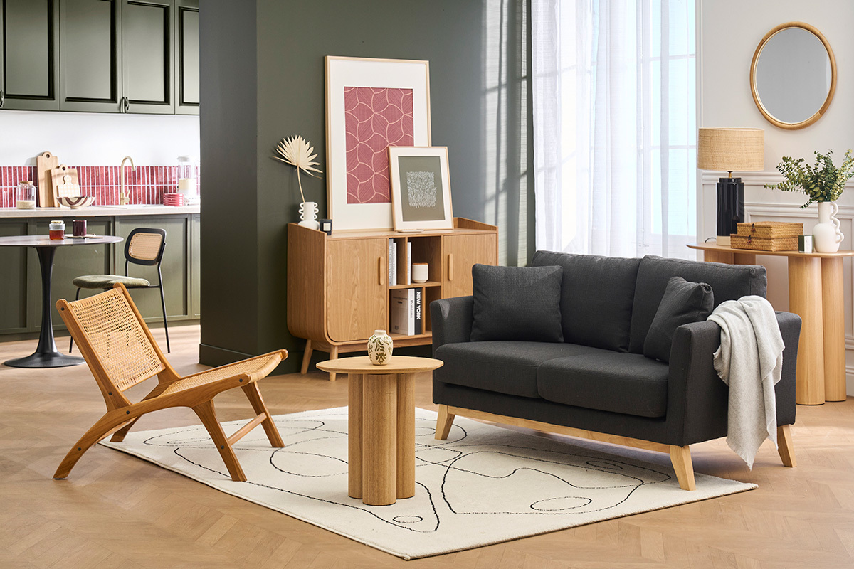 Divano a 2 posti OSLO grigio scuro su tappeto, con tavolino e sedia in legno, vista frontale.