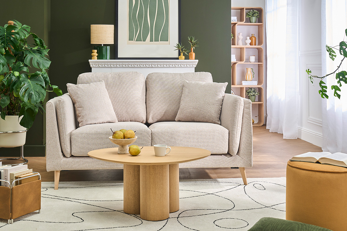 Divano scandinavo per 2 persone VOGUE in tessuto beige con cuscini, vista frontale in un soggiorno di stile.