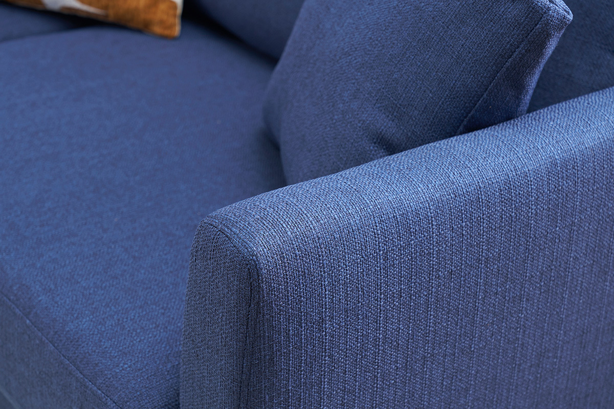 Primo piano sul bracciolo del divano scandinavo in tessuto blu scuro.