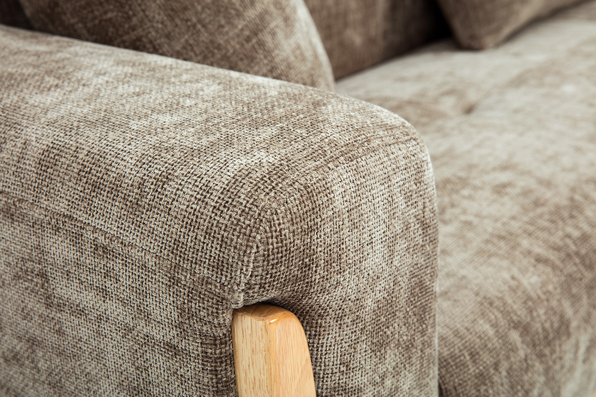 Primo piano sul bracciolo del divano scandinavo effetto velluto taupe e legno chiaro.