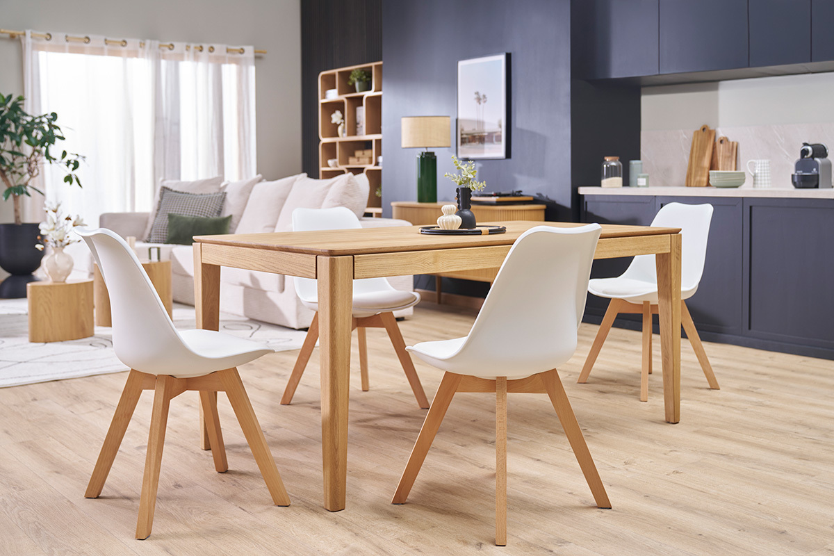 Set di 4 sedie scandinave bianche con gambe in legno chiaro attorno a un tavolo in legno.