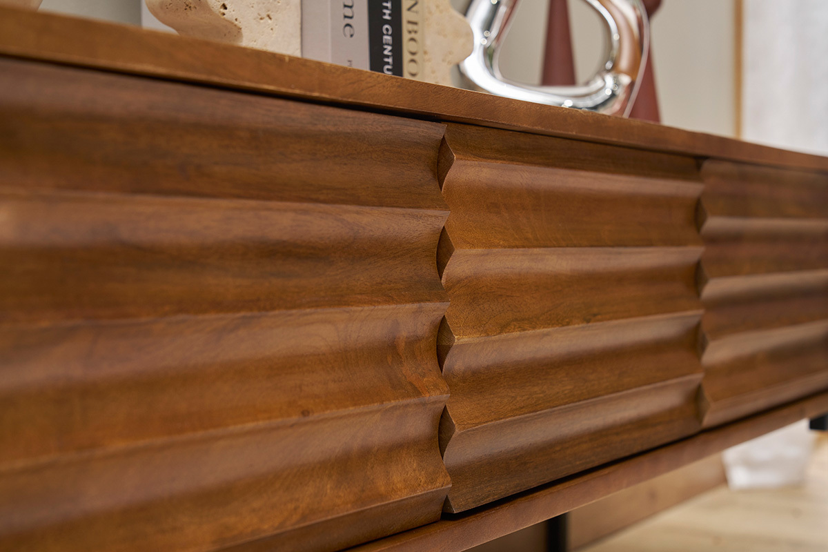 Primo piano sul mobile TV ONDA in legno massello di mango con motivi intagliati.