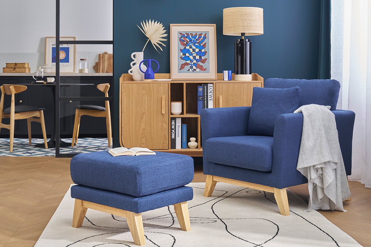 Pouf poggiapiedi blu scuro e legno OSLO, vista frontale, su tappeto con poltrona abbinata.