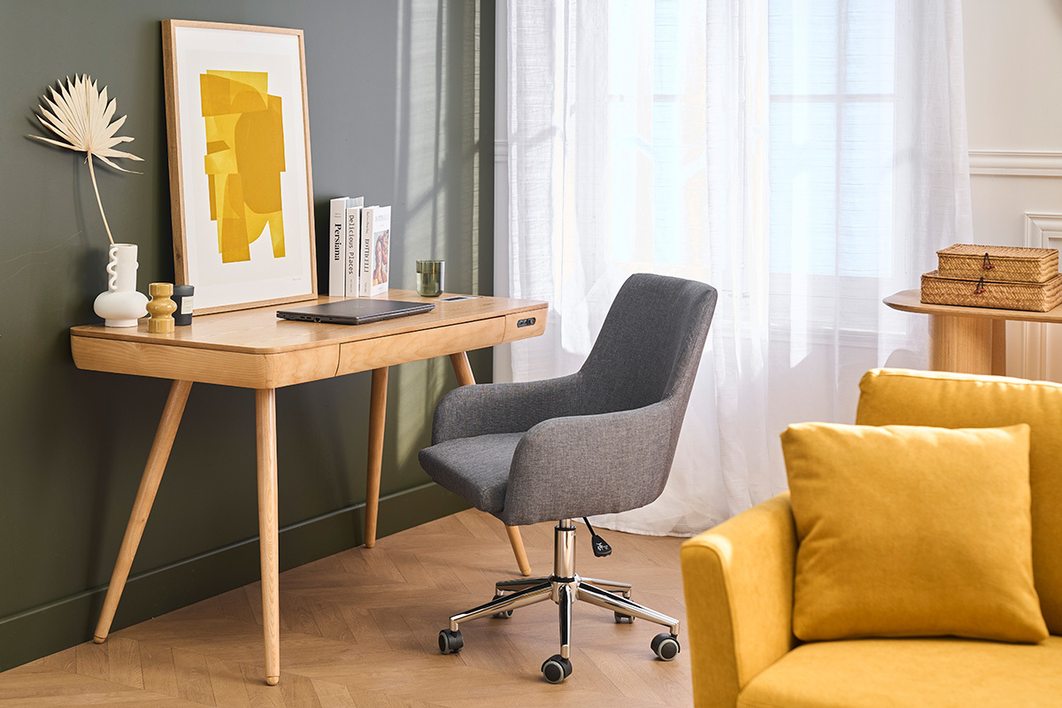 Sedia da ufficio grigia SHANA su ruote, davanti a una scrivania in legno, vista d'angolo.