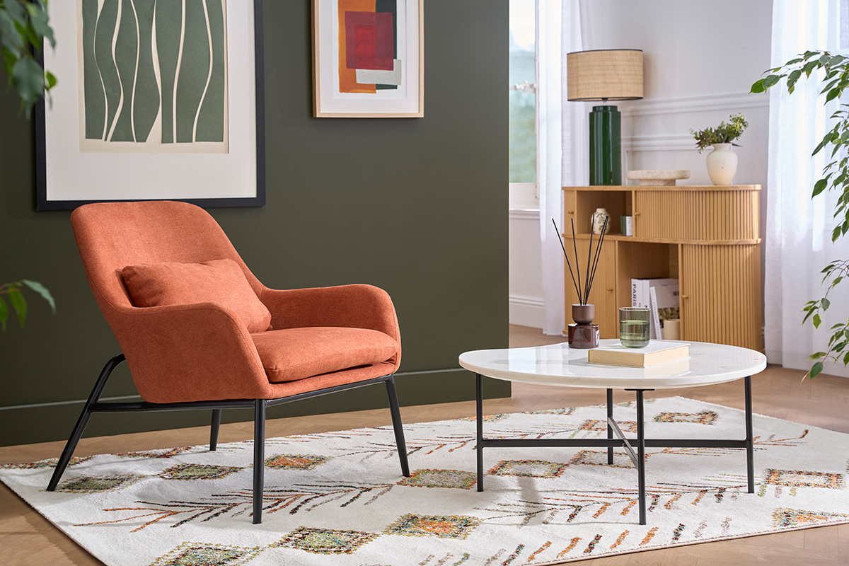 Poltrona design terra bruciata, tessuto effetto velluto, piedi metallo nero, vista laterale in un salotto moderno.