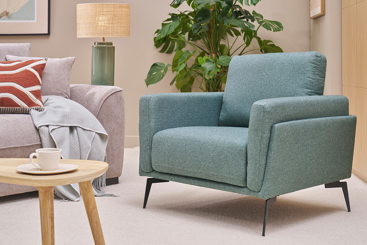 Poltrona design verde grigio MOSCO con struttura in metallo nero, vista in un soggiorno.