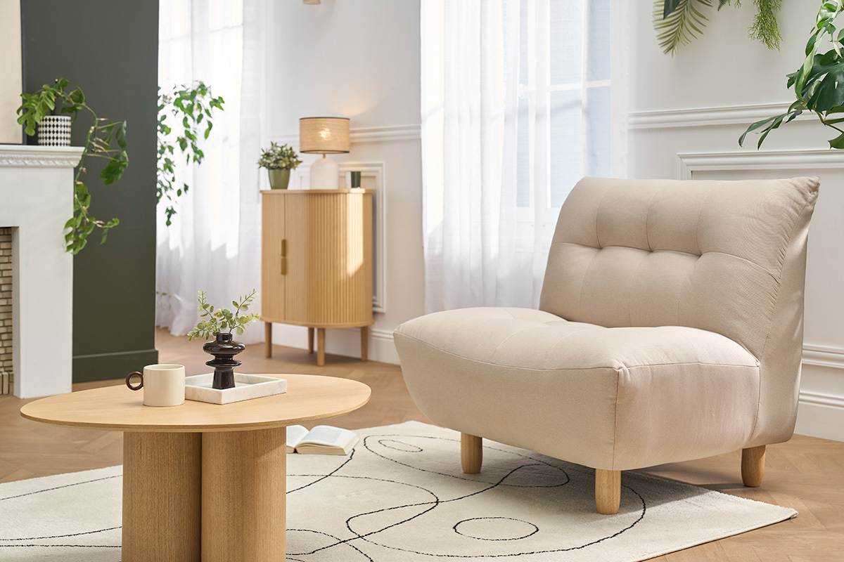 Poltrona scandinava beige YUMI con cuscini in un soggiorno moderno, vista da 3/4.