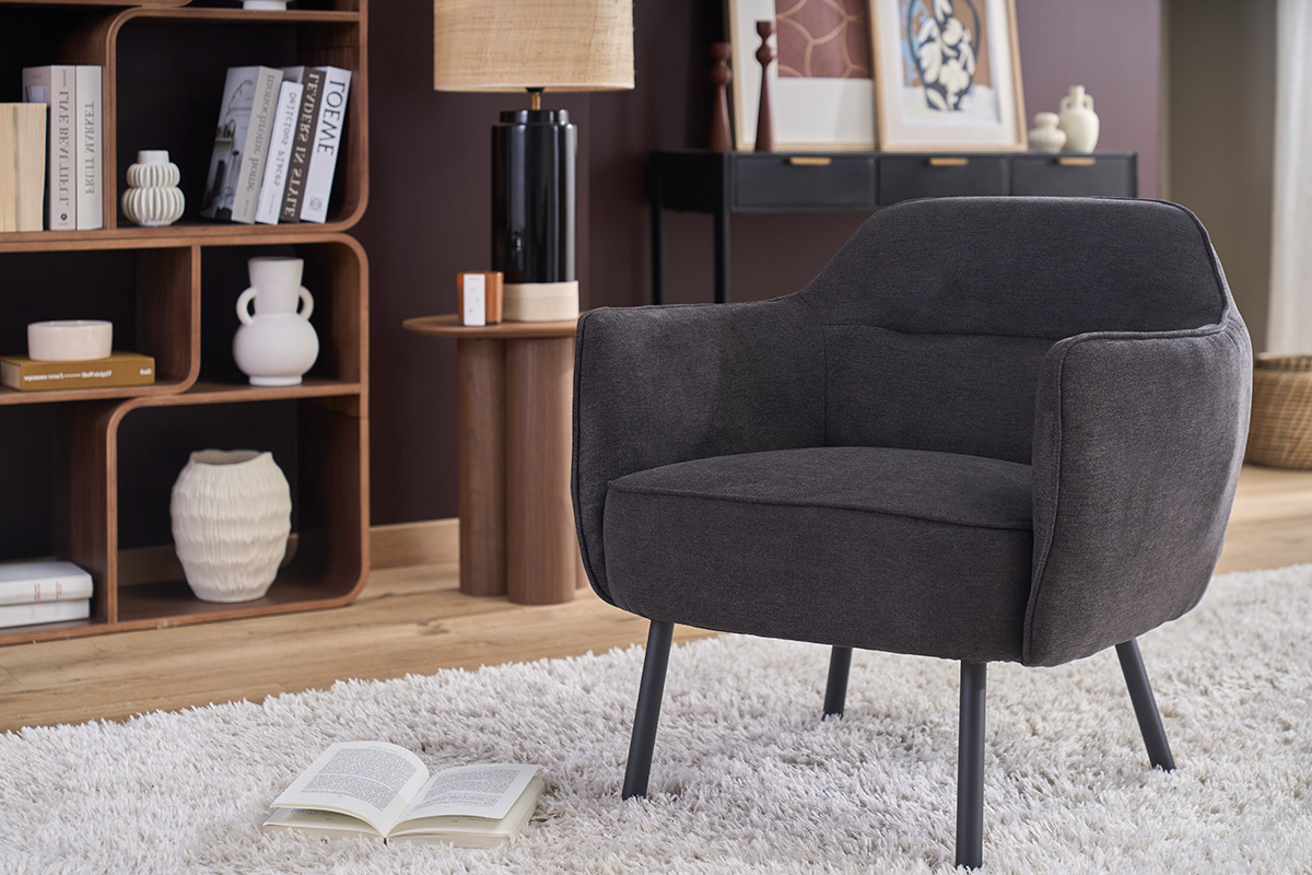Poltrona di design LAURENS in tessuto velluto grigio scuro, vista tre quarti con arredamento interno.