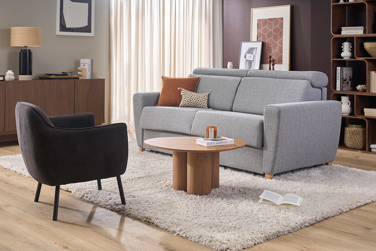 Poltrona di design in tessuto effetto velluto grigio scuro, vista laterale, con mobili moderni intorno.