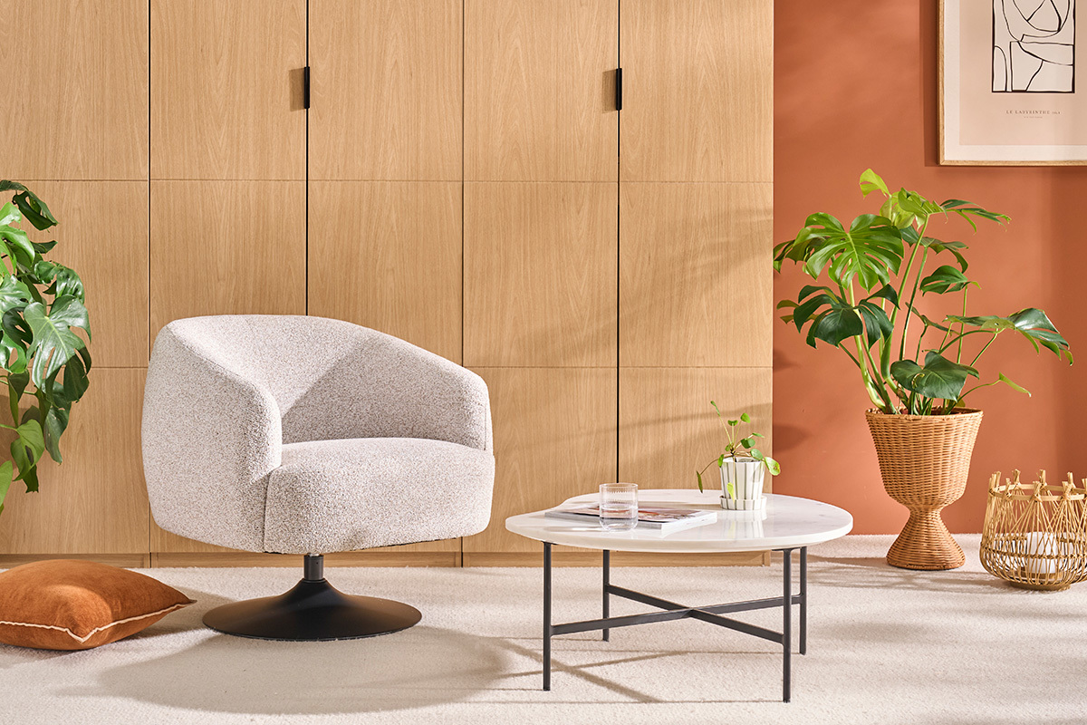 Poltrona BOWIE in tessuto effetto ciniglia terra bruciata, vista da 3/4 con tavolino e pianta.