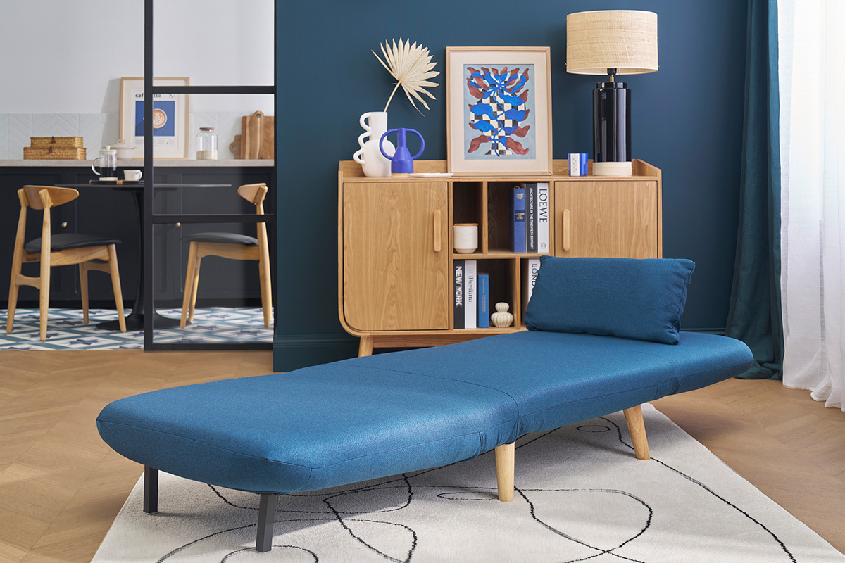 Poltrona letto blu scuro AMIKO aperta in un soggiorno scandinavo.