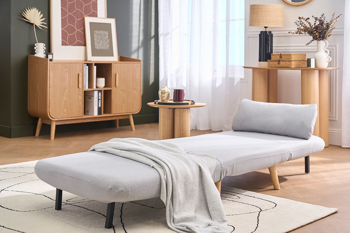 Poltrona letto AMIKO in grigio chiaro in stile scandinavo, presentata in posizione letto in un interno moderno.