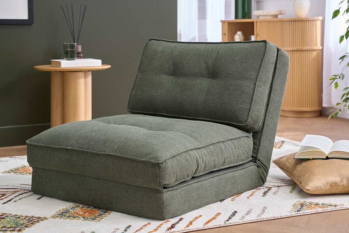 Poltrona letto singola in tessuto verde kaki SALLY, vista laterale in un salone.