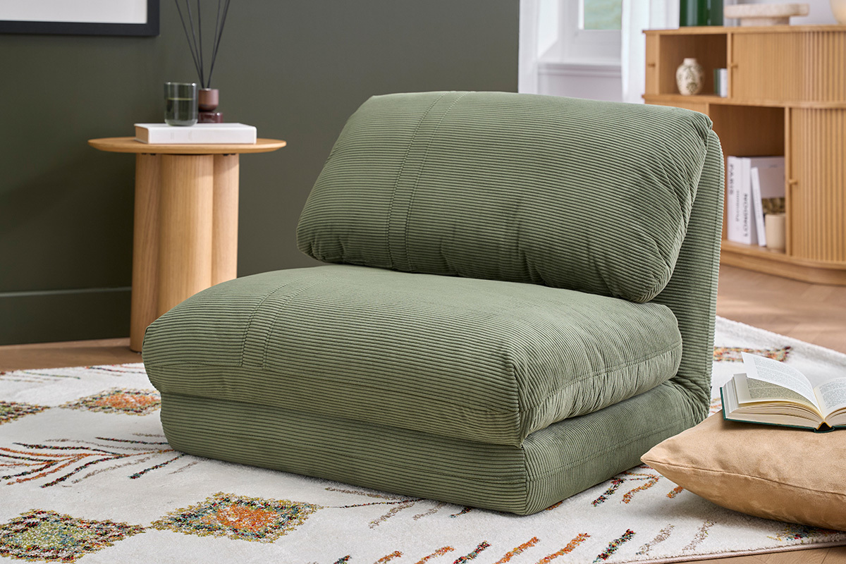 Poltrona letto in velluto a coste verde kaki, vista da 3/4 in un salotto.