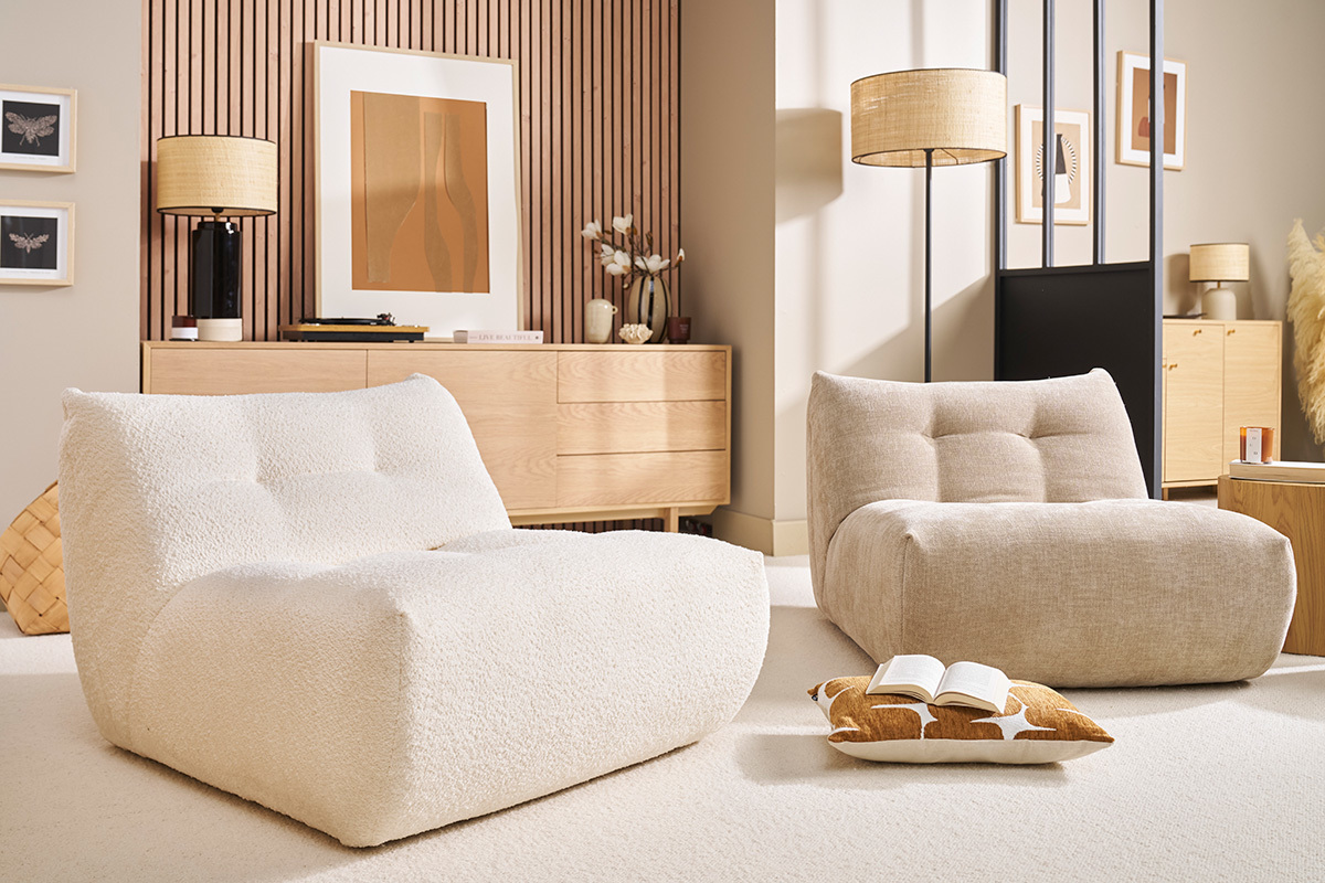 Due poltrone lounge in un soggiorno moderno, con cuscino e libro per terra.