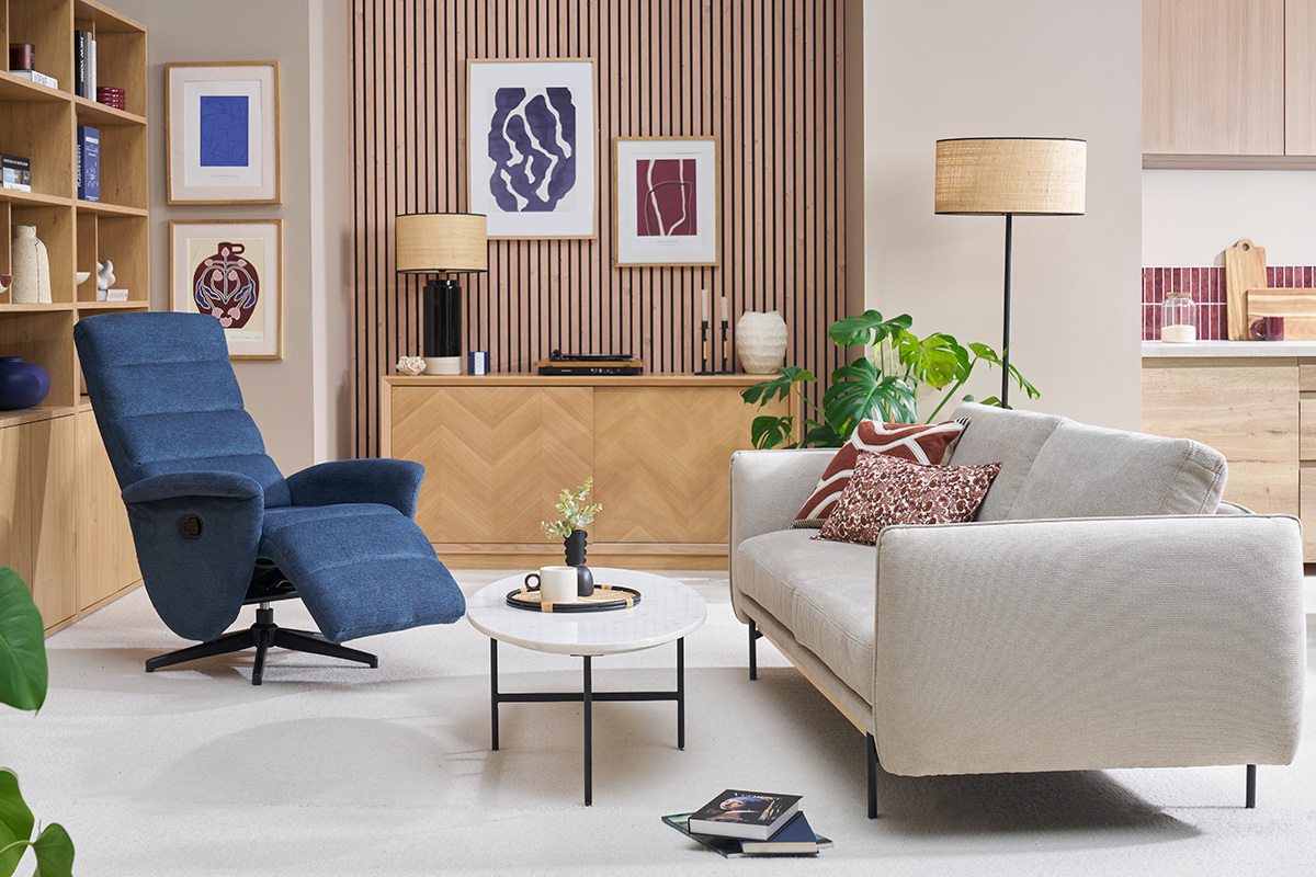 Soggiorno con poltrona girevole relax in tessuto blu e divano chiaro.