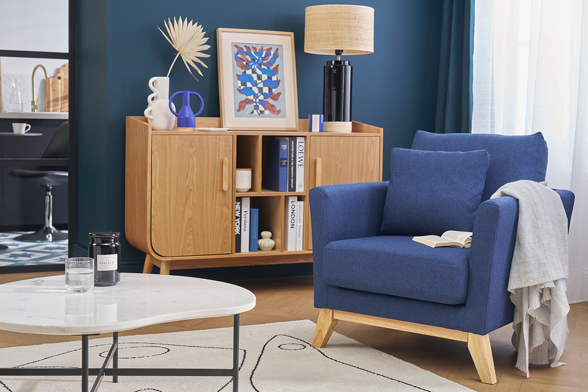 Poltrona scandinava blu scuro e legno chiaro in un soggiorno moderno.