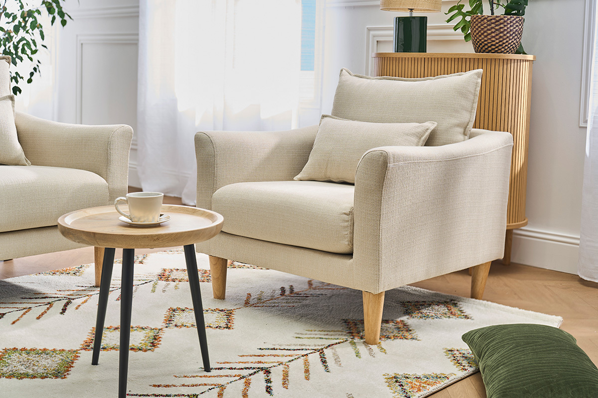 Poltrona scandinava beige con cuscini, tavolino da caff�, vista da tre quarti.