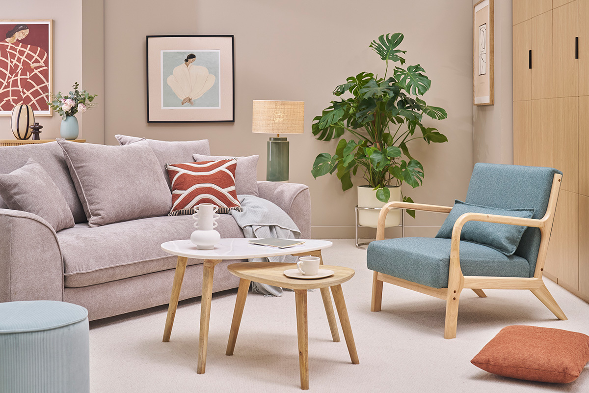 Poltrona verde grigio e legno chiaro DERRY in un soggiorno scandinavo con divano, tavoli e piante.