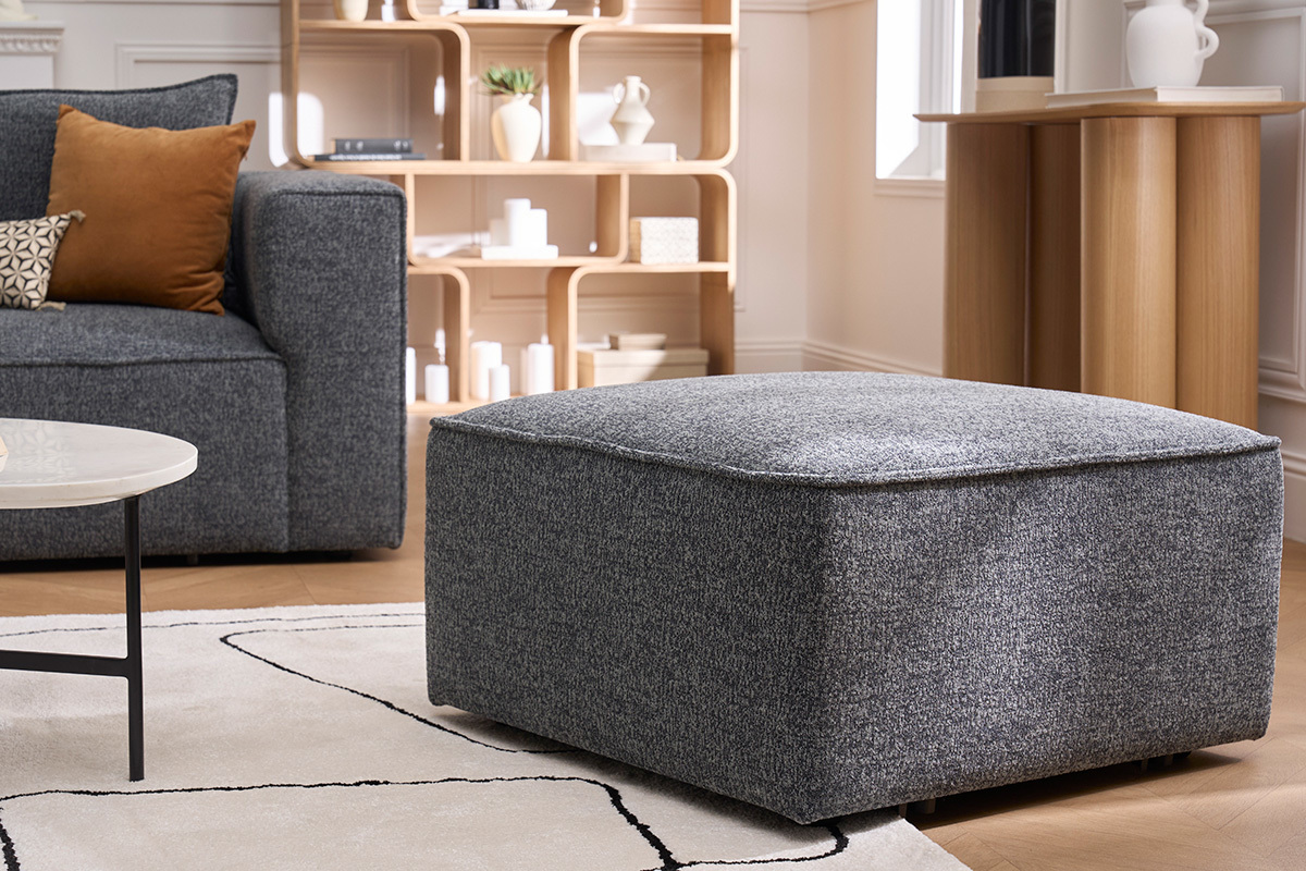 Pouf quadrato KERRY in tessuto grigio, integrato in un soggiorno moderno.