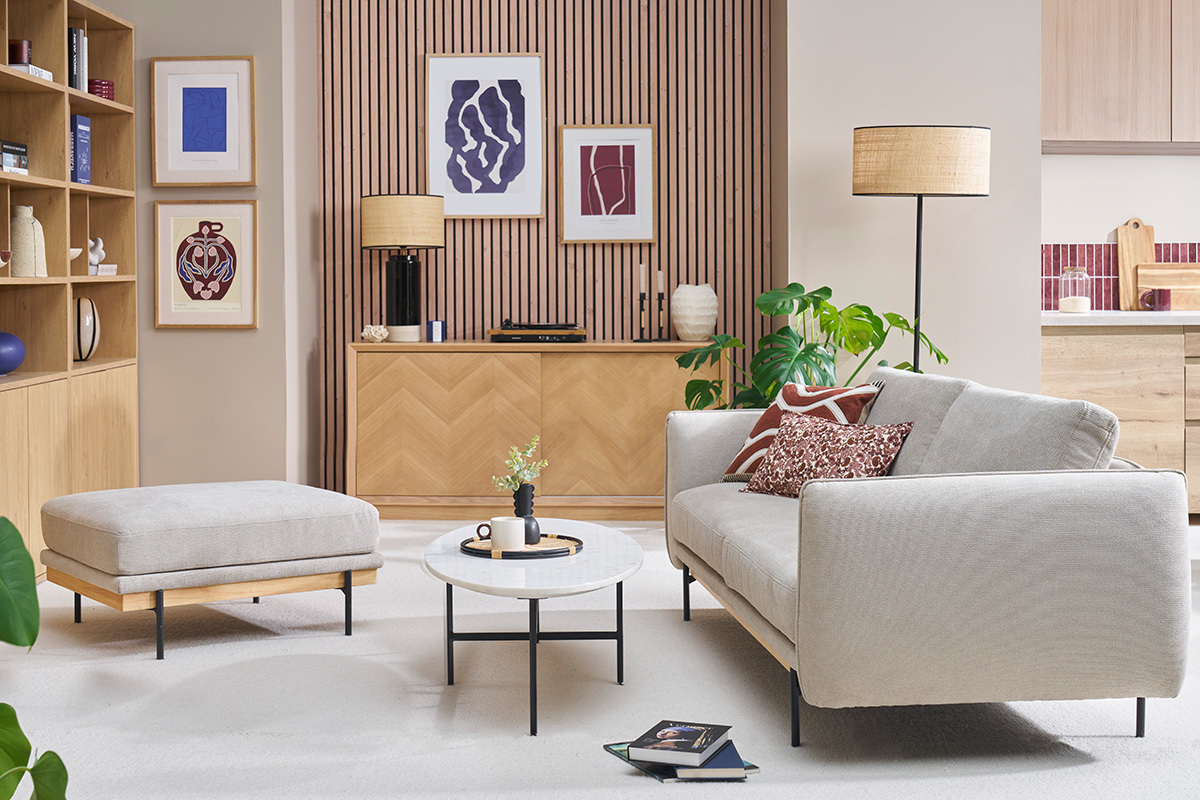 Pouf poggiapiedi in tessuto beige in un soggiorno moderno, angolazione laterale.