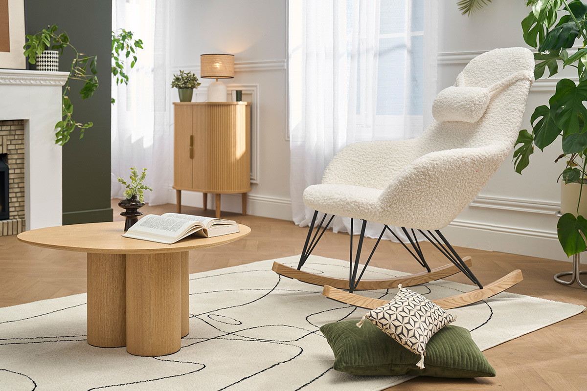 Poltrona a dondolo scandinava JHENE in tessuto effetto pelle di pecora bianco, con base in metallo nero e legno chiaro.