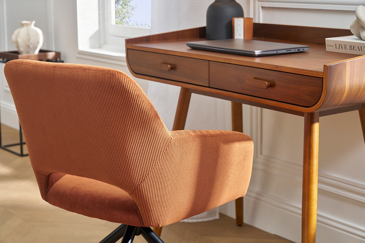 Sedia girevole in velluto a coste color terra bruciata davanti a una scrivania in legno, vista posteriore.