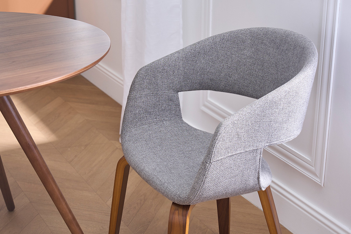 Sedia di design in tessuto grigio con gambe in legno scuro, vista da vicino.