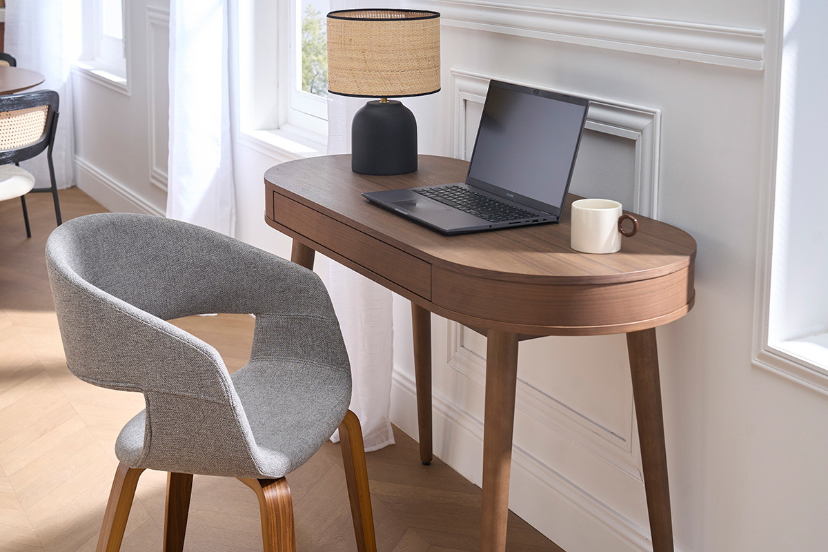 Sedia di design in tessuto grigio con gambe in legno scuro, vista laterale vicino a una scrivania.