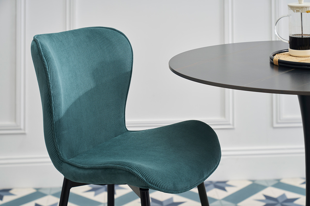 Sedia design in velluto a coste blu petrolio con gambe in metallo nero, vista laterale.