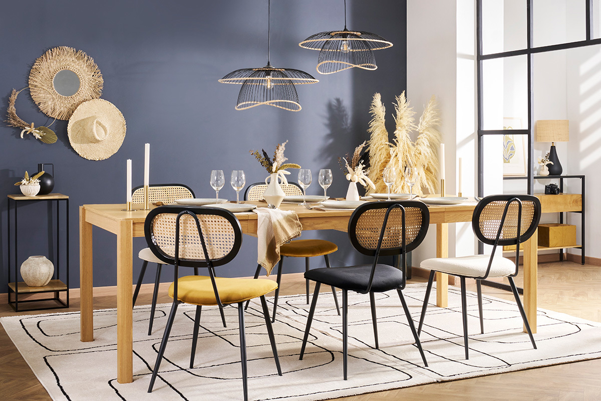 Sedie di design in velluto e rattan intorno a un tavolo in legno chiaro.